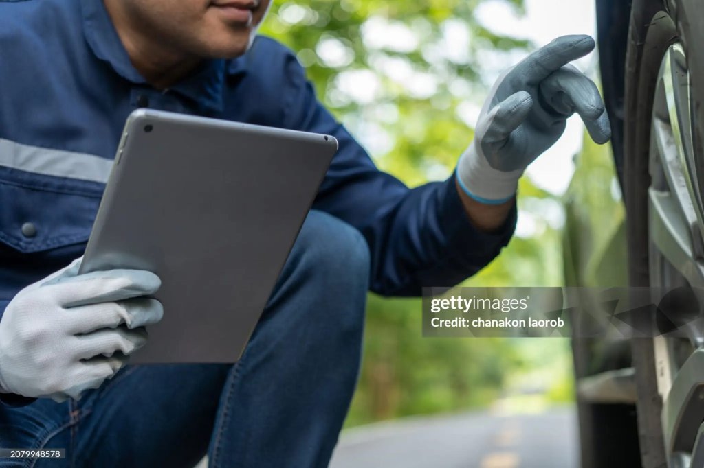 Technician inspecting a vehicle with a tablet.